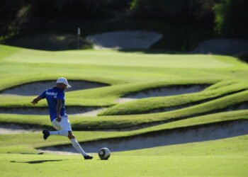 Ballon de soccer près d'un trou sur un parcours de footgolf, illustrant la fusion du football et du golf.