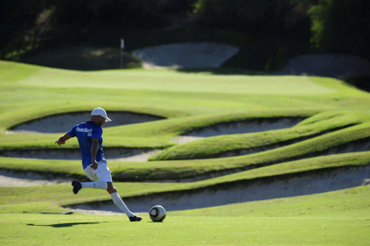 Ballon de soccer près d'un trou sur un parcours de footgolf, illustrant la fusion du football et du golf.